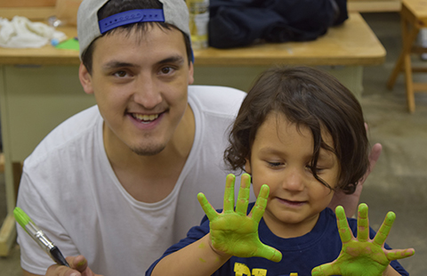 TVTC student with child showing painted hands at a family day visit of the facility.